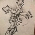 Фото тату: эскиз креста, обвитого четками, выполненный в реалистичном стиле с использованием штриховки и теней.