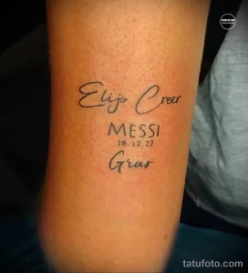 Фото татуировки с надписью 'Elijo Creer', именем 'MESSI' и датой '18.12.22'. Лаконичный дизайн и четкие линии.