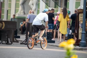 Фотография BMX-райдера на фоне городской архитектуры с видимой татуировкой на руке, демонстрирующей стиль и индивидуальность.