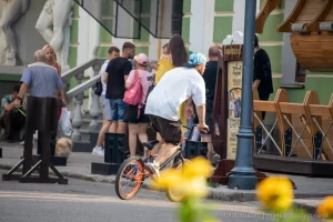 Фотография BMX-райдера на фоне городской архитектуры с видимой татуировкой на руке, демонстрирующей стиль и индивидуальность.