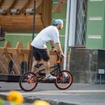 Фотография BMX-райдера, выполняющего трюк, с видимой татуировкой на руке, демонстрирующей динамику и индивидуальность.