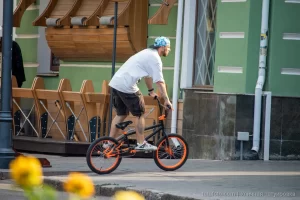 Фотография BMX-райдера, выполняющего трюк, с видимой татуировкой на руке, демонстрирующей динамику и индивидуальность.