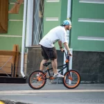 Фотография BMX-райдера в движении с видимой татуировкой на руке, демонстрирующая энергию и свободу уличной культуры.