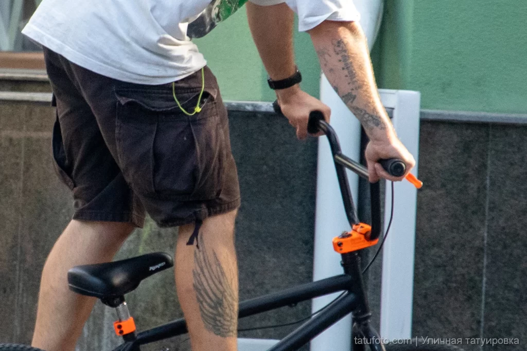 Велосипедист в движении с татуировками на руке и ноге 7