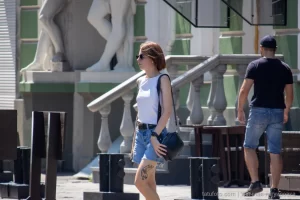 Фото тату зайца на бедре женщины, идущей по улице с черной сумкой. Минималистичный рисунок татуировки, уличная фотография.