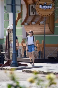 Фото тату зайца на бедре женщины, идущей по улице с черной сумкой. Минималистичный рисунок татуировки, уличная фотография.