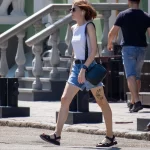 Фото тату зайца на бедре женщины, идущей по улице в наушниках. Минималистичный рисунок татуировки, уличная фотография.