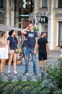 Фото тату: мужчина с татуировкой дракона на руке, стоящий на улице. Рисунок выполнен в традиционном японском стиле.