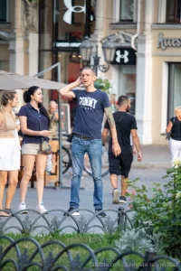 Фото тату: мужчина с татуировкой дракона и другими рисунками на руке, стоящий на улице. Рисунок выполнен в традиционном японском стиле.