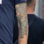 Зеленая татуировка с драконом на левой руке мужчины 6