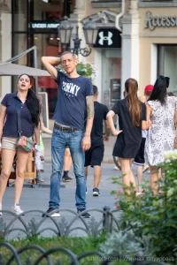 Фото тату: мужчина с татуировкой дракона на руке, стоящий на улице. Рисунок выполнен в традиционном японском стиле.