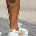 Красивая татуировка с контуром цветка и надписью на правой икре девушки 5