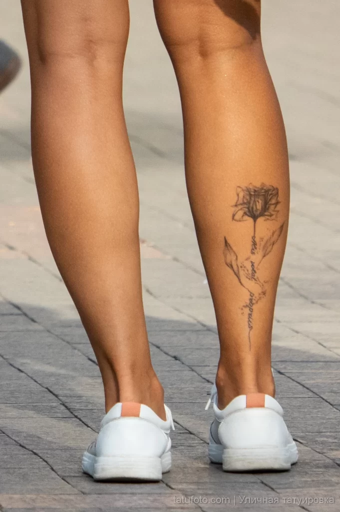 Красивая татуировка с контуром цветка и надписью на правой икре девушки 8