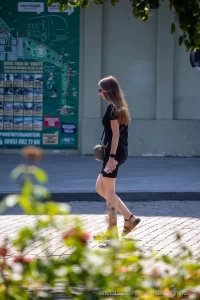 Фото тату на голени, изображающее реалистичные цветы и летящую бабочку. Черно-серые тона, детализированная проработка.