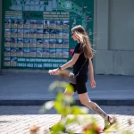 Фото тату на голени, изображающее реалистичные цветы и летящую бабочку. Черно-серые тона, детализированная проработка.