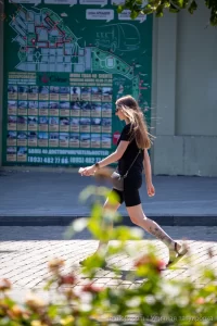 Фото тату на голени, изображающее реалистичные цветы и летящую бабочку. Черно-серые тона, детализированная проработка.