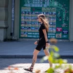 Фото тату на голени девушки, изображающее реалистичные цветы и летящую бабочку. Черно-серые тона, детализированная проработка.