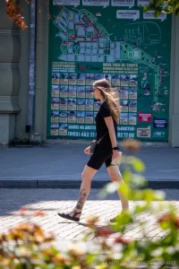 Фото тату на голени девушки, изображающее реалистичные цветы и летящую бабочку. Черно-серые тона, детализированная проработка.