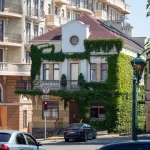 Фото улицы с красивой архитектурой и женщиной с татуировкой на руке. Татуировка выполнена в акварельном стиле.