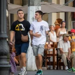 Фотография двух мужчин, идущих по улице, у одного из которых видны татуировки на руке. Татуировки выполнены в черном цвете и имеют сложный узор.