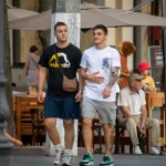 Фотография двух мужчин, идущих по улице, у одного из которых видны татуировки на руке. Татуировки выполнены в черном цвете и имеют сложный узор.