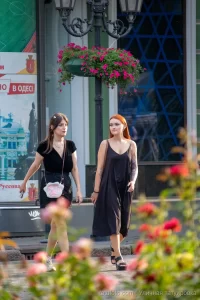Фотография двух девушек, идущих по улице, у одной из которых видна татуировка на руке. Татуировка выполнена в темных тонах и имеет сложный узор.