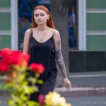 Фото тату на руке девушки: детализированный рисунок с изображением лица, цветов и узоров, выполненный в ярких цветах, на фоне цветущих роз.
