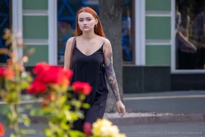 Фото тату на руке девушки: детализированный рисунок с изображением лица, цветов и узоров, выполненный в ярких цветах, на фоне цветущих роз.