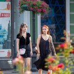 Фотография двух девушек, идущих по улице, у одной из которых видна татуировка на руке. Татуировка выполнена в темных тонах и имеет сложный узор.