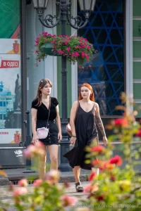 Фотография двух девушек, идущих по улице, у одной из которых видна татуировка на руке. Татуировка выполнена в темных тонах и имеет сложный узор.