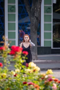 Фото тату на руке девушки: детализированный рисунок с изображением лица, цветов и узоров, выполненный в ярких цветах, на фоне цветущих роз.