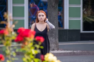 Фото тату на руке девушки: детализированный рисунок с изображением лица, цветов и узоров, выполненный в ярких цветах, на фоне цветущих роз.