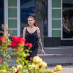 Фото тату на руке девушки: детализированный рисунок с изображением лица, цветов и узоров, выполненный в ярких цветах, на фоне цветущих роз.