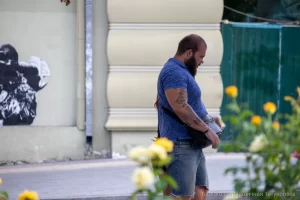 Фото тату на руке мужчины: детализированные рисунки, покрывающие плечо и предплечье, в сочетании с бородой и повседневной одеждой.