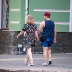 Фото тату на руке и ноге мужчины, идущего с девушкой. Видны небольшие, но детализированные рисунки, выполненные в черном цвете.