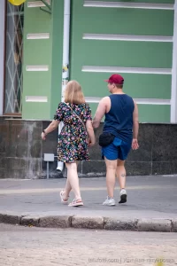 Фото тату на руке и ноге мужчины, идущего с девушкой. Видны небольшие, но детализированные рисунки, выполненные в черном цвете.