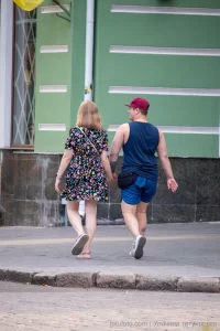 Фото тату на руке и ноге мужчины, идущего с девушкой. Видны небольшие, но детализированные рисунки, выполненные в черном цвете.