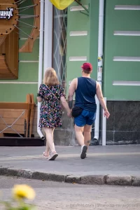 Фото тату на руке и ноге мужчины, идущего с девушкой. Видны небольшие, но детализированные рисунки, выполненные в черном цвете.