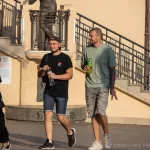 Фотография двух мужчин, идущих по улице. У одного из них видна татуировка на руке в стиле блэкворк, покрывающая большую часть руки.
