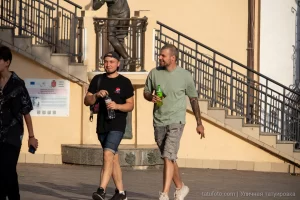 Фотография двух мужчин, идущих по улице. У одного из них видна татуировка на руке в стиле блэкворк, покрывающая большую часть руки.