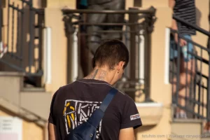Фото тату на шее мужчины: темный геометрический узор, выполненный в стиле трайбл. Видна часть татуировки на плече и руке.