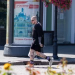 Фото тату на ногах мужчины, идущего по улице. Видны детализированные рисунки на голенях и бедрах, выполненные в реалистичном стиле.