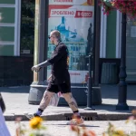 Фото тату на ногах и рукаве мужчины, идущего по улице. Видны детализированные рисунки, выполненные в реалистичном стиле.