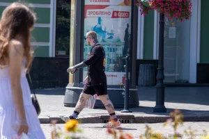 Фото тату на ногах и рукаве мужчины, идущего по улице. Видны детализированные рисунки, выполненные в реалистичном стиле.
