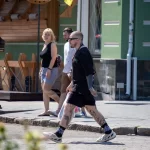 Фото тату на ногах мужчины, идущего по улице. Видны детализированные рисунки на голенях и бедрах, выполненные в реалистичном стиле.