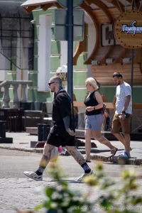 Фото тату на ногах мужчины, идущего по улице. Видны детализированные рисунки на голенях и бедрах, выполненные в реалистичном стиле.