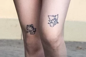 Фото парных тату на коленях: два рисунка Hello Kitty, выполненные в черном цвете. Милый и игривый дизайн.