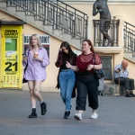 Фото тату на ноге девушки: небольшой рисунок, расположенный на внешней стороне бедра. Современный уличный стиль, яркая одежда.
