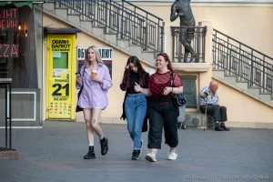 Фото тату на ноге девушки: небольшой рисунок, расположенный на внешней стороне бедра. Современный уличный стиль, яркая одежда.