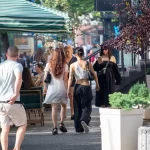 Фото тату на руке девушки: небольшой черный рисунок, напоминающий маску или лицо, выполненный в минималистичном стиле. Современный эскиз татуировки.
